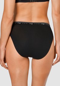 Slip di cotone nero con una texture liscia, caratterizzato da un elastico con logo e piccoli dettagli. Progettato per comfort e copertura.