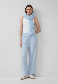 Pantalons rayés bleu clair avec une taille élastique, associés à un débardeur blanc et une écharpe bleu clair, complétés par des baskets blanches.