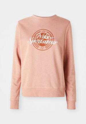 Light pink sweatshirt made of soft fabric, featuring a round logo with "Nike Sportwear" and decorative elements in darker pink.