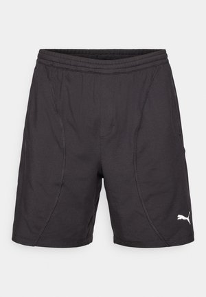 Czarne spodenki sportowe wykonane z materiału syntetycznego, z elastycznym pasem, bocznymi szwami i białym logo Pumy na dolnej prawej stronie.