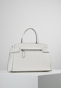 Valkoinen nahkalaukku, jossa on jämäkkä muoto, kaksinkertaiset kahvat ja etupuolella vetoketjullinen tasku. Korostaa ompeluyksityiskohtia ja teksturoitua pintaa.