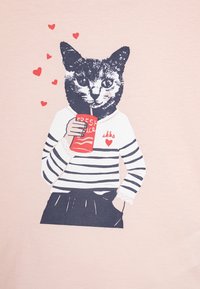 Maglietta a maniche lunghe a righe bianche e nere con dettagli in pizzo, che presenta un'immagine di un gatto con una bevanda rossa circondato da simboli a forma di cuore rossi.