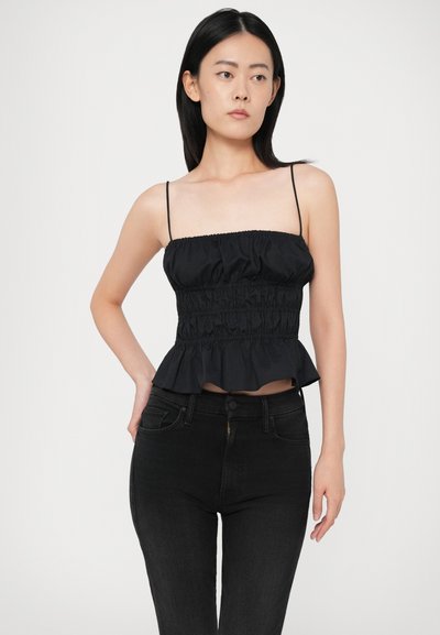 Top preto cropped com alças finas, apresentando uma textura franzida e uma bainha com babados. Combinado com jeans pretos de cintura alta.