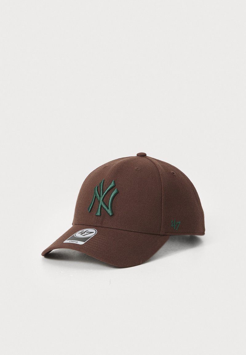 Brun baseball cap med et grønt broderet New York-logo foran og et lille 47-emblem på siden. Glat stoftekstur, buet skygge.