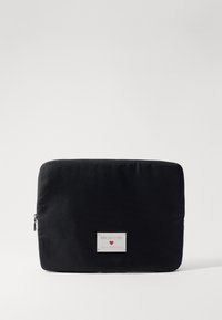 Funda para portátil de tela negra con textura suave. Presenta una etiqueta de logo plateada y un cierre con cremallera. Forma rectangular, diseño minimalista.