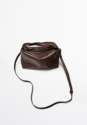 Dunkelbraune Leder-Umhängetasche mit langem verstellbarem Riemen und Reißverschluss oben, liegend auf einer weißen Oberfläche.