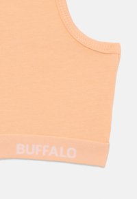 Ferskenfarget bomullssports-bh med rund utringning, myk stoff og hvit "BUFFALO" logo på bunnbåndet. Glatt tekstur og sømløst design.