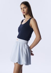 Top in cotone a coste blu navy abbinato a una gonna corta a righe blu chiaro con vita elasticizzata e orlo scallop.