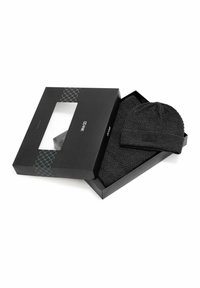 Czarna dzianinowa czapka i szalik ustawione w czarnym pudełku z przezroczystym okienkiem. Szalik ma wzór w jodełkę.