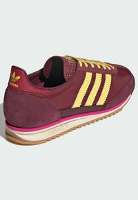 Bordeaux sneakers med gule accenter, net- og ruskindsmaterialer, struktureret hæl, snørebånd og multicolorer sål. Tre striber på siden.