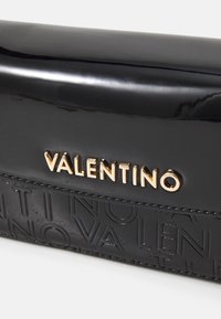 Sort patentlæder clutch med præget "Valentino"-logo og hardware i guldtonet. Slankt design med en glat, blank finish.