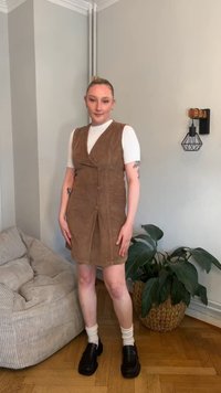 Hnedé kordové šaty s výstrihom do V, zapínaním na gombíky a voľným strihom. Kombinované s bielym tričkom a čiernymi topánkami na platforme.
