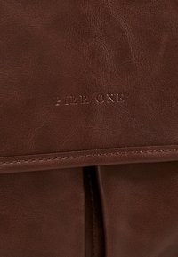 Hnědá kožená taška s hladkou texturou, horizontálními švy a embosovaným logem "PIER ONE" na přední straně.