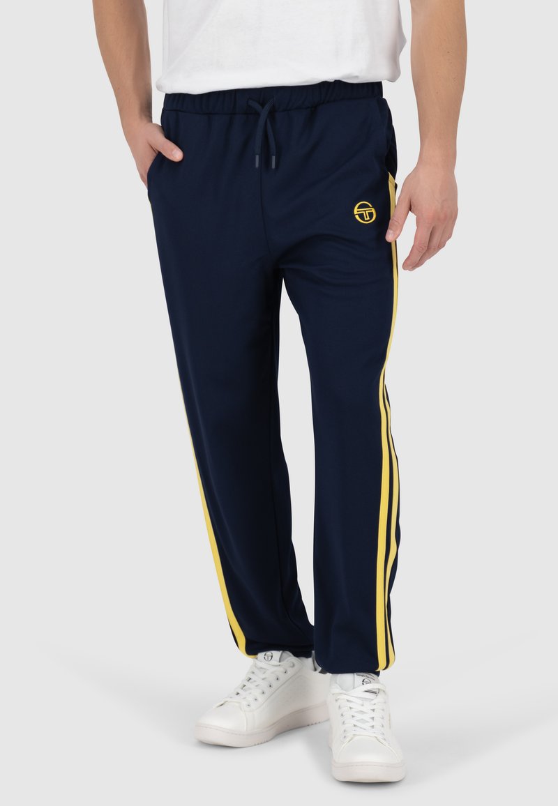 Marineblaue Sporthosen aus leichtem Stoff, mit gelben Seitenstreifen, einem elastischen Bund mit Kordelzug und einem Logodetail am Bein.