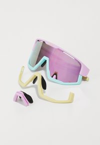Sportzonnebril met een gedurfd geometrisch montuur in pastelroze en mintgroen, voorzien van paarse getinte lenzen en verstelbare rubberen accenten.