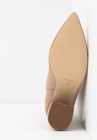 Nude zamszowe szpilki z wydłużonym noskiem i gładką gumową podeszwą. Rozmiar 37 nadrukowany na wkładce, widoczna tekstura na obcasie.