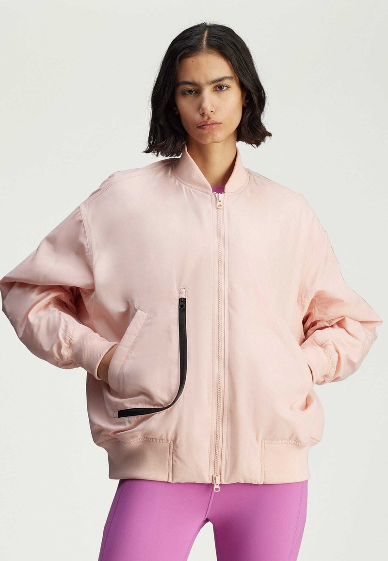 Light pink bomber jacket with a zip front, ribbed collar, and black zipper detail. Features loose fit and side pockets.