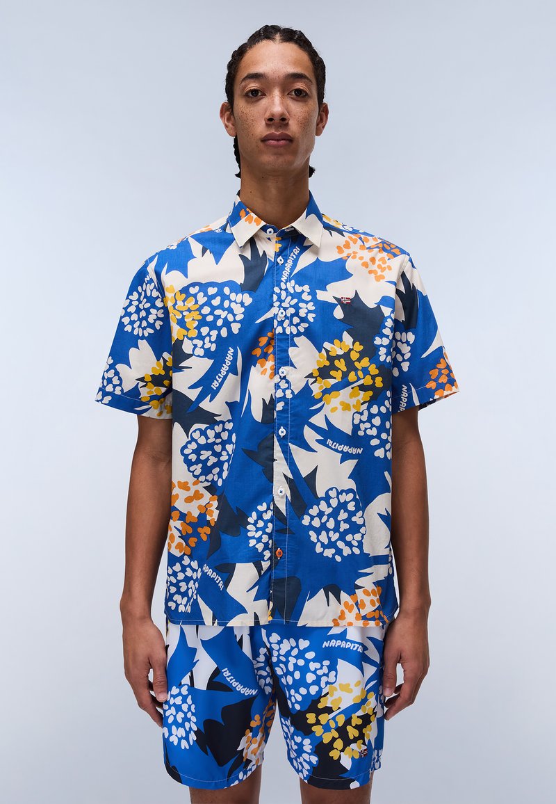 Kortærmet skjorte med knaplukning og matchende shorts, prydet med en lys blå baggrund og blomsterdesigns i creme, orange og mørkeblå.