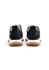 Marineblaues Wildleder- und Leder-Sportcoupé mit einer weißen Zwischensohle und einer strukturierten, hellbraunen Laufsohle; verfügt über eine Zuglasche und einen gepolsterten Kragen.