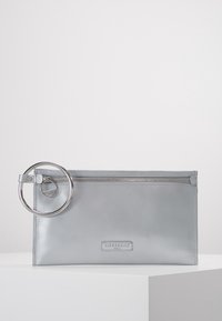 Grå läderclutch med en slät yta, utrustad med ett topsdragkedja och en stor metallring som accent på sidan.