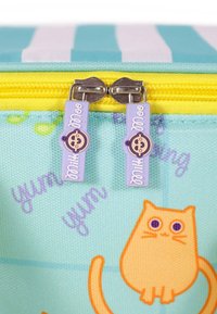 Two purple zipper pulls with smiling baby faces on a blue and yellow bag featuring an orange cat and purple text.