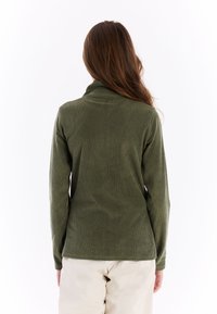 Groene geribde pullover met een hoge kraag en lange mouwen, met een zachte textuur. De zoomlijn is recht en bevindt zich op de heup.