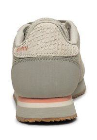 Helle graue Sneaker-Ferse mit texturiertem Oberteil, subtilen rosa und weißen Mittelsohlenstreifen sowie sichtbarem braunem Gummisohle-Profil.