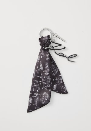 Black keychain with a printed fabric ribbon featuring white designs. Includes a metal charm spelling "Karl" in a cursive font. Silver hardware.