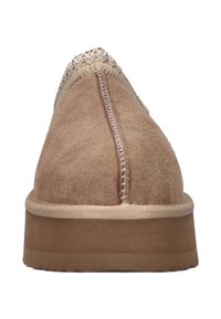 Vue de face d'une chaussure en daim beige à enfiler, avec des coutures détaillées et une bordure décorative tissée sur l'orteil.