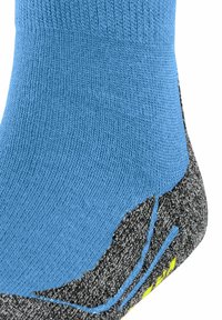 Calcetín deportivo azul acanalado con una plantilla texturizada gris, que presenta acentos amarillos y un diseño curvado para mayor comodidad y soporte.