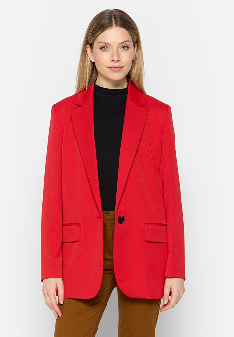 Rode blazer met een getailleerde pasvorm, met notch revers, sluiting met één knop en twee voorkwakken, gecombineerd met een zwarte coltrui.