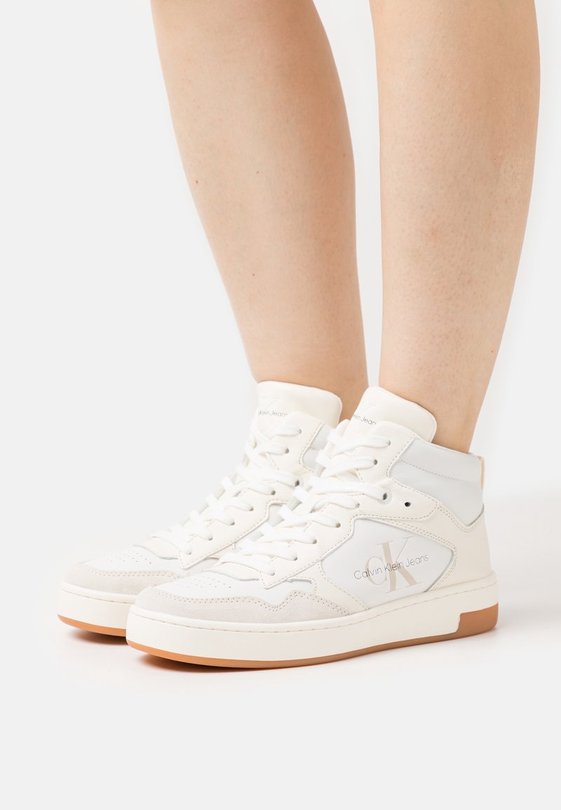 Białe sneakersy za kostkę wykonane z ekoskóry i zamszu, z logo na boku, teksturowanymi panelami i gumową podeszwą.