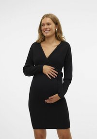 Abito premaman nero in maglia a coste con scollatura a V profonda, maniche lunghe e dettaglio della cintura legata in vita. Silhouette aderente.