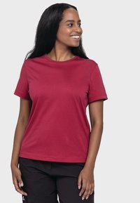 Rotes Baumwoll-T-Shirt mit kurzen Ärmeln, einem runden Halsausschnitt und einer glatten Textur; kombiniert mit schwarzen Hosen. Schlichte Gestaltung ohne sichtbare Muster.