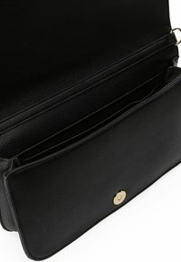 Borsa a mano in pelle nera con superficie texture, dotata di chiusura a scatto dorata e numerosi scomparti interni.