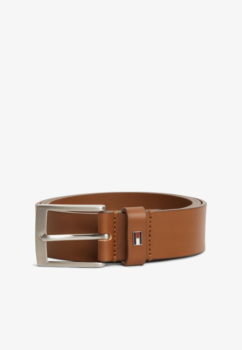 Ceinture en cuir marron avec boucle rectangulaire argentée et petite étiquette logo rectangulaire avec un motif rouge, blanc et noir près de la boucle.