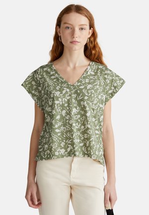 Groene top met bloemenpatroon, een V-hals en korte, brede mouwen. Gemaakt van lichtgewicht stof met een comfortabele pasvorm. Gecombineerd met lichtgekleurde broeken.