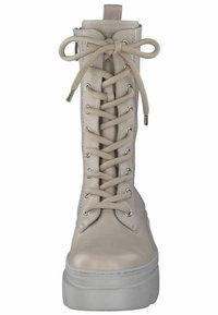 Stivaletti alla caviglia in pelle beige con lacci, punta tonda, superficie testurizzata e una spessa suola piattaforma bianca. Presentano occhielli argentati e cuciture decorative.