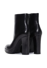 Bottines noires en cuir lisse, avec un haut talon bloc, une semelle à plateforme et une fermeture éclair à l'arrière.
