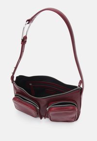 Sac à bandoulière en cuir bourgogne avec une sangle réglable, deux poches zippées à l'avant et un compartiment principal zippé avec doublure intérieure noire.