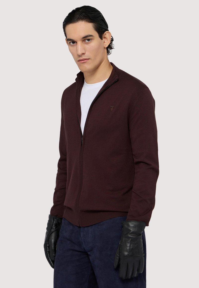 Bordový svetr na zip s jemným logem, žebrovanými manžetami a hladkou texturou, doplněný černými koženými rukavicemi.