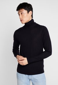 Sort turtleneck sweater lavet af blødt stof, med lange ærmer, en tætsiddende pasform og et diskret logo detalje på brystet.