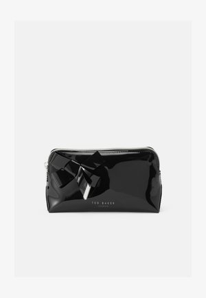 Bolso de charol negro con cierre de cremallera, que presenta un gran lazo decorativo y herrajes plateados, marcado con "Ted Baker London".