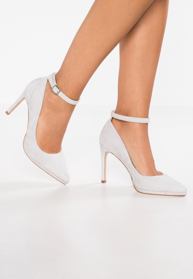 Chaussures à talons hauts en daim gris avec un bout pointu et une bride à la cheville. Les talons sont fins et élevés, complétant ainsi le design élégant.