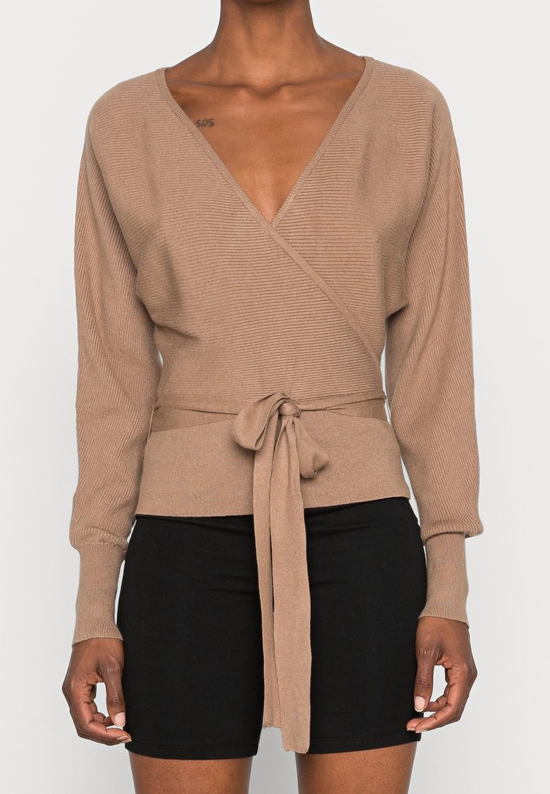 Brown ribbed wrap sweater with a deep V-neck and long sleeves, featuring a tied waist detail. Soft texture, fitted design.