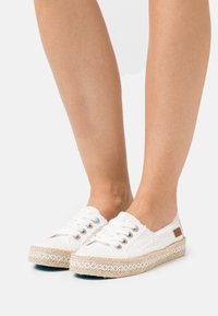 Vita canvas-espadrillos med flätad sula av jute, utrustade med metallöglor och snörning. Prydda med en liten brun logotypmärke.