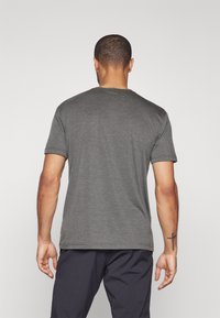 Camiseta corta de manga gris con cuello redondo. Tela suave y texturizada; diseño sencillo. Presenta mangas enrolladas y un ajuste entallado en los hombros.