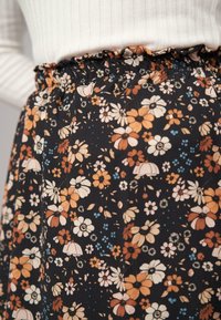 Fustă florală cu un fundal negru, având flori portocalii, crem și albastre. Talie elastică cu detalii volan, material ușor.