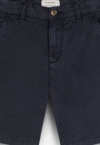 Pantaloni corti in cotone blu navy con chiusura a bottone, tasche frontali e una finitura pulita e texture. Presentano cuciture minime e un design elegante.