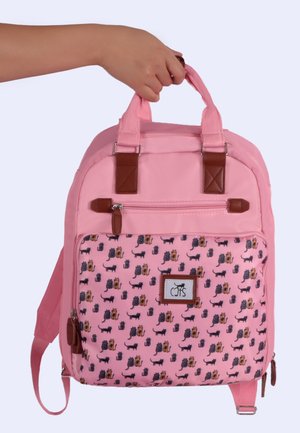 Hand holding pink backpack with brown straps and front pocket patterned with various small cat illustrations.